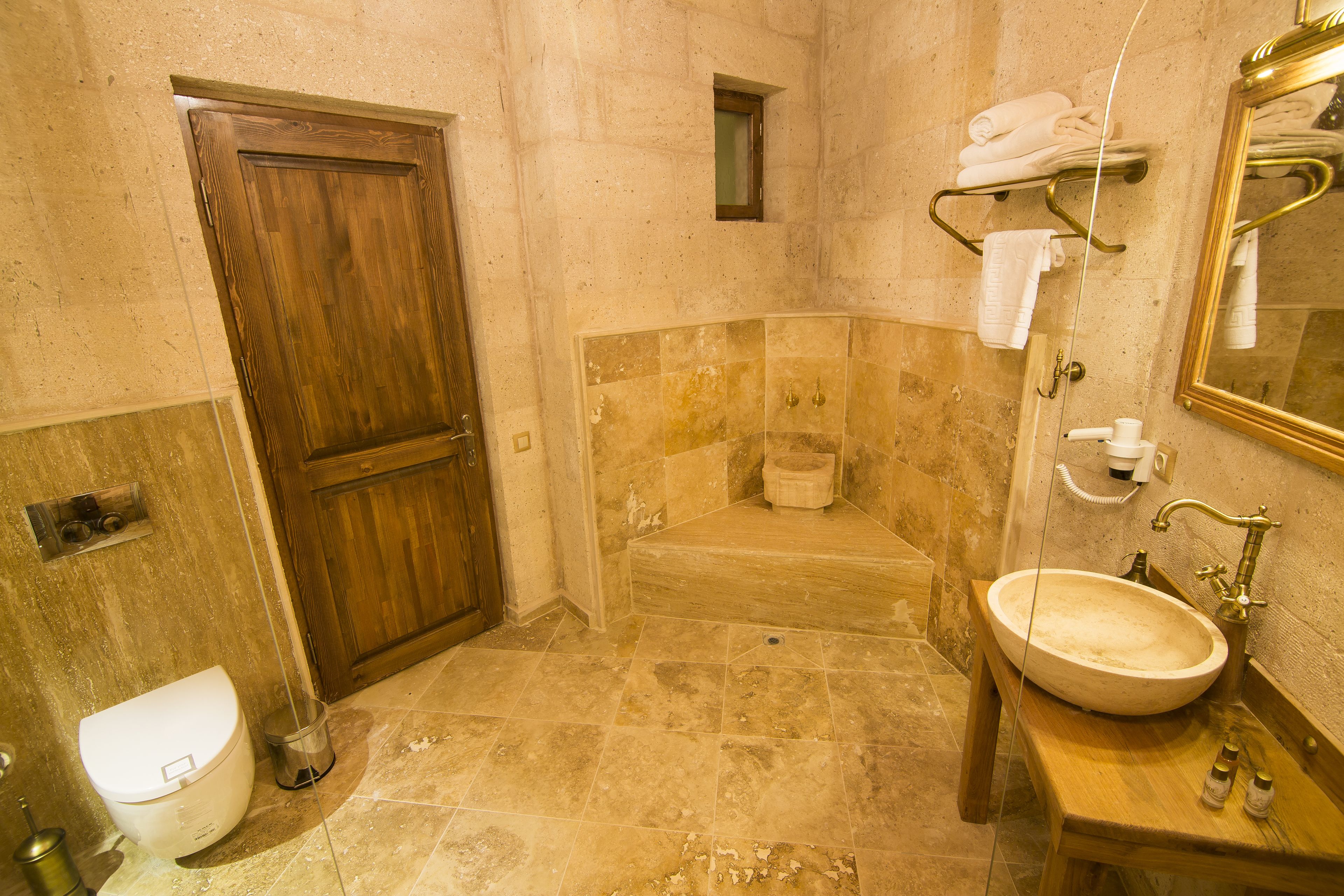 A bathroom with a wooden door, a bathtub, a sink, and a mirror.