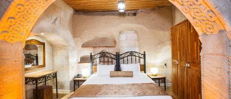A rustic bedroom with a wooden bed, a nightstand, a mirror, and a wardrobe.