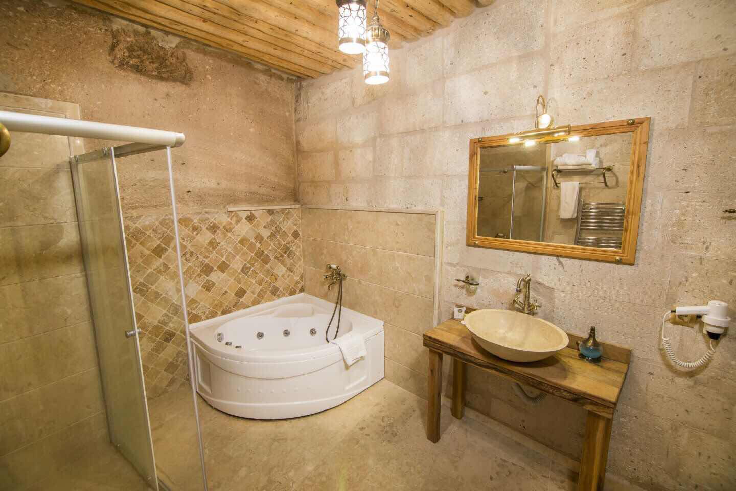 A bathroom with a glass-enclosed shower, a freestanding bathtub, a wooden vanity with a sink, and a mirror with a towel rack.