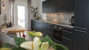 A modern kitchen with dark cabinets, a built-in oven, and a dining area with a table and chairs.