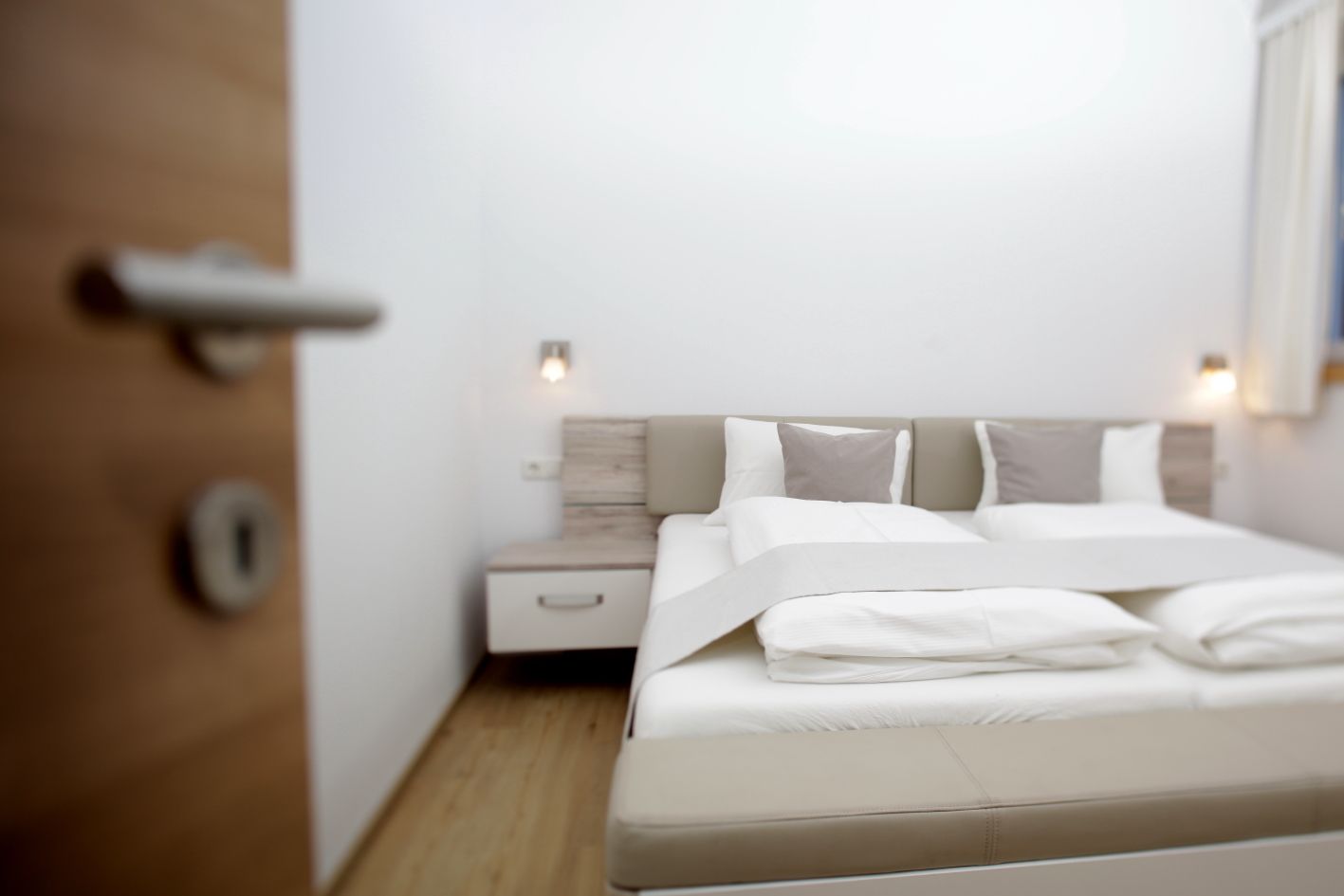 A modern bedroom with a bed, bedside tables, and a door.