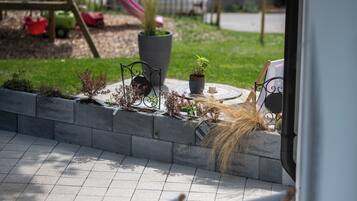 Relax in a serene outdoor space with a view of the playground, surrounded by lush greenery and a patio seating area.