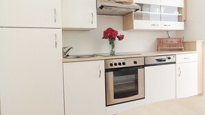 Une cuisine moderne avec des armoires blanches, un four en acier inoxydable et un plan de travail en bois.