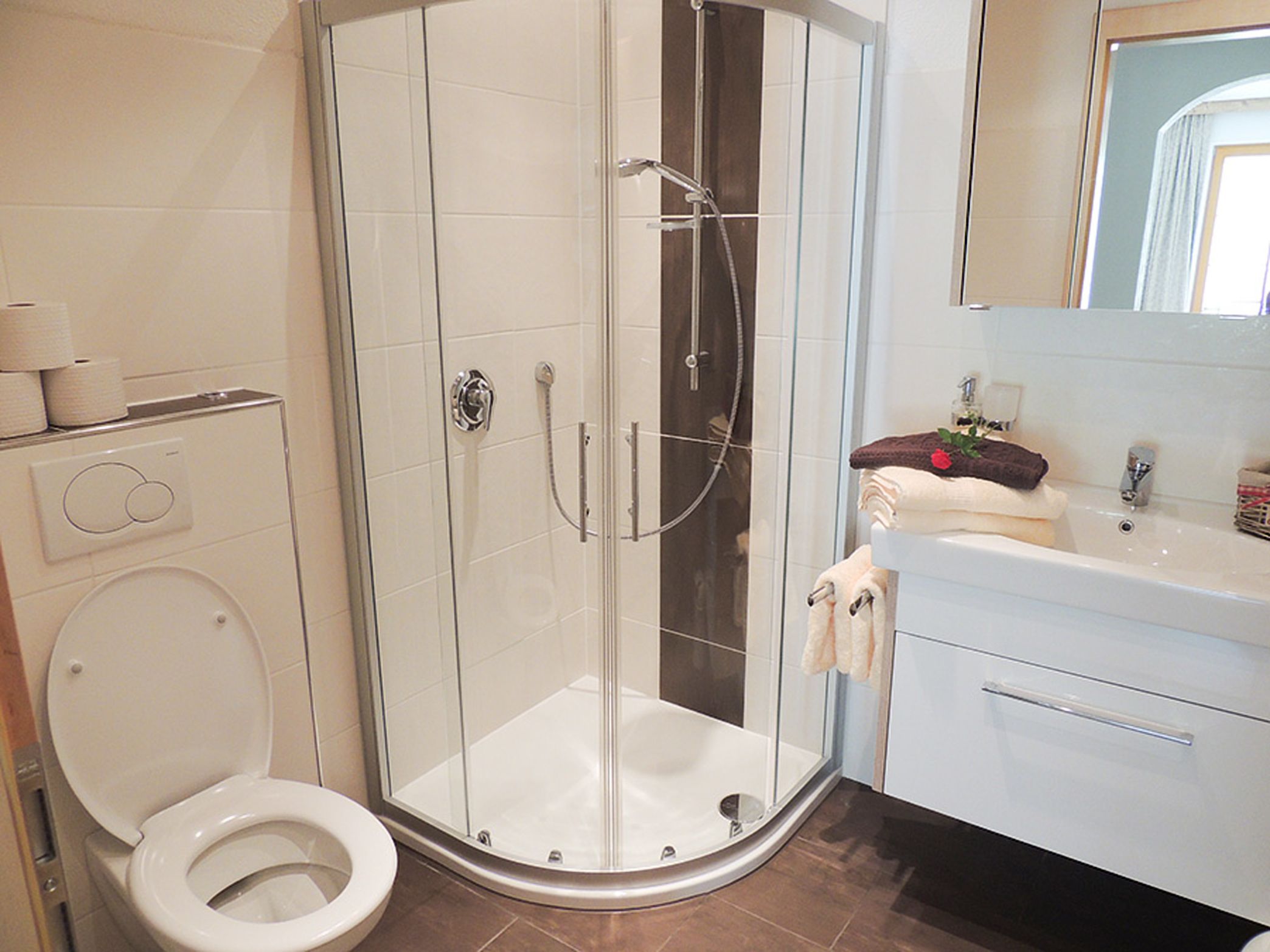 Un baño moderno con ducha envuelta en vidrio, inodoro y tocador con espejo.