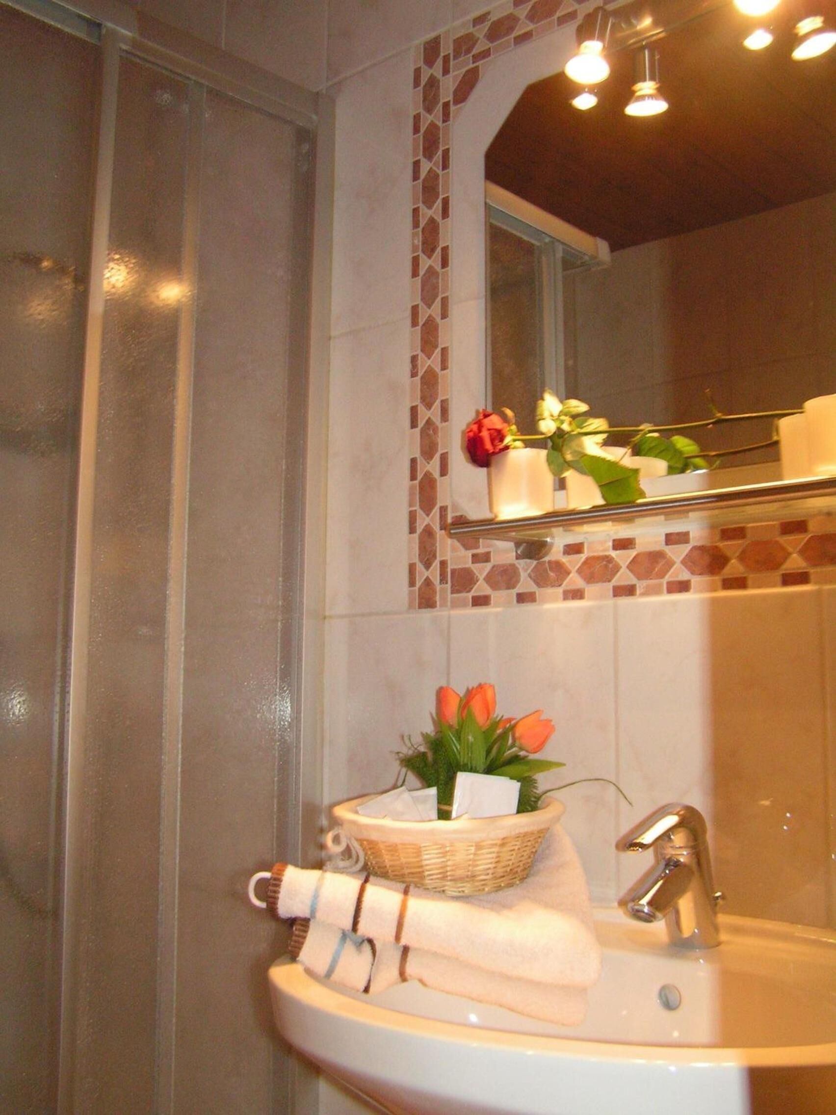 A bathroom with a sink, a mirror, and a shower.