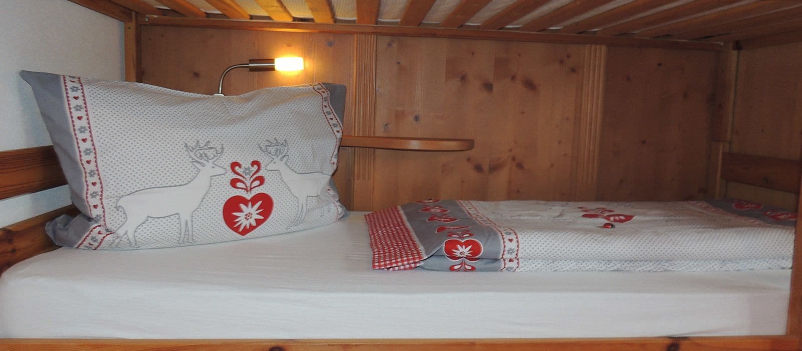 A wooden bunk bed with a headboard and a bedside table.