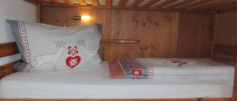 A wooden bunk bed with a headboard and a bedside table.