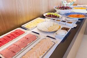 A buffet table with various food items including sliced meats, cheeses, fruits, and vegetables. - Garça Real Hotel & Spa (Montemor-o-Velho)