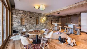 Cozy space with a rustic charm, featuring a stone wall, plush armchairs, and a comfortable sofa.