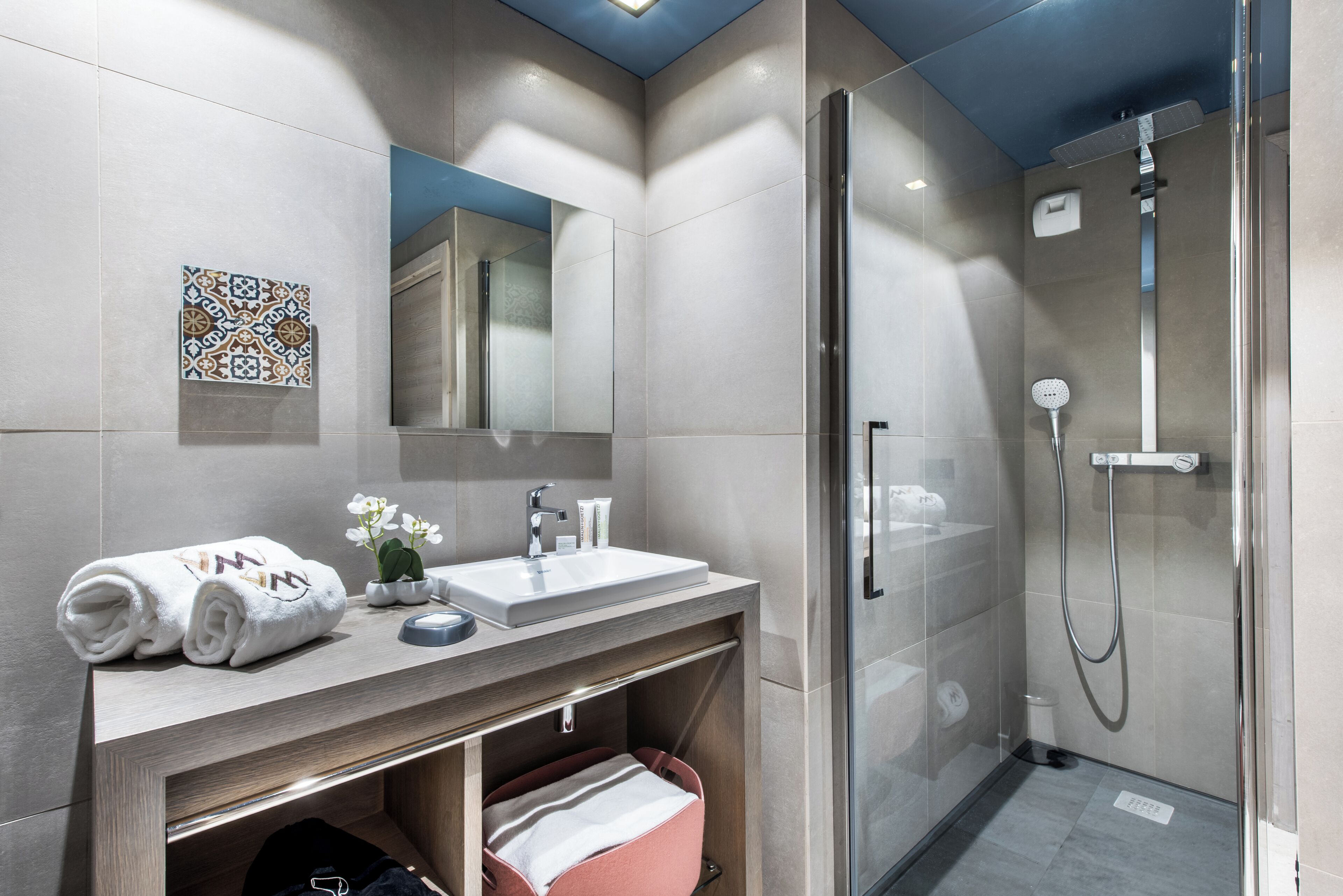 Une salle de bain moderne avec une douche à parois de verre, un lavabo avec un miroir et un porte-serviettes.