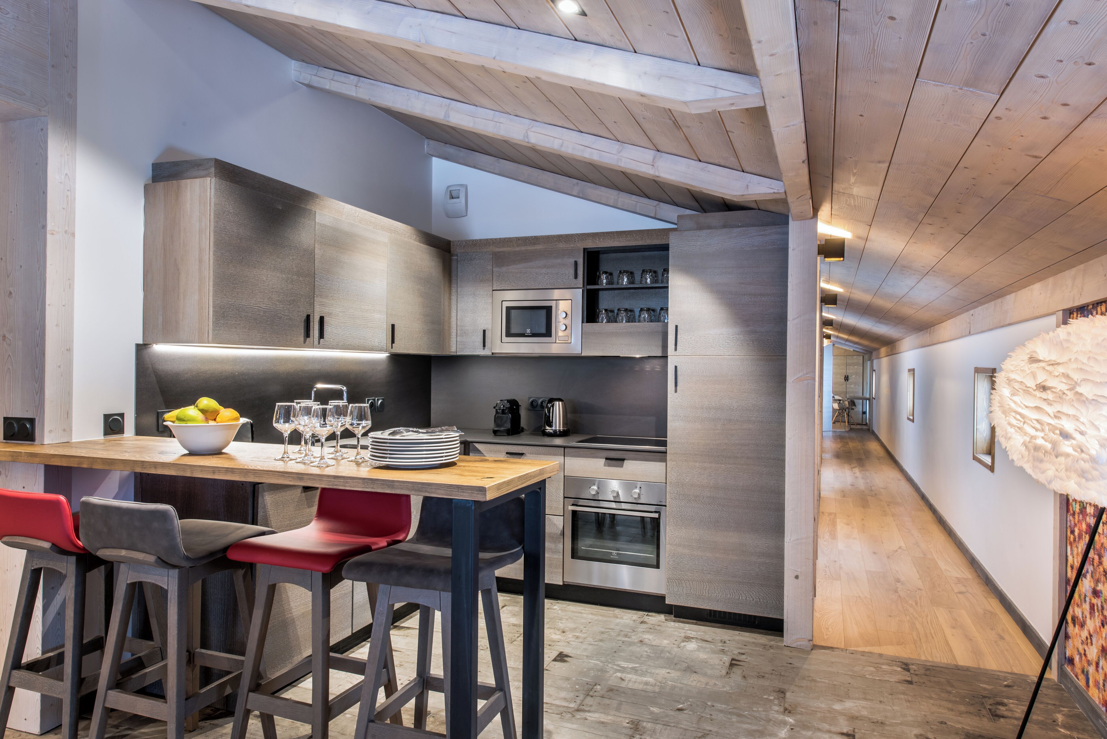 A modern kitchen with wooden cabinets, a stainless steel refrigerator, and a wooden dining table with bar stools.