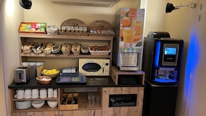 Una kitchenette equipada con tostadora, microondas, cafetera y un bol de frutas.