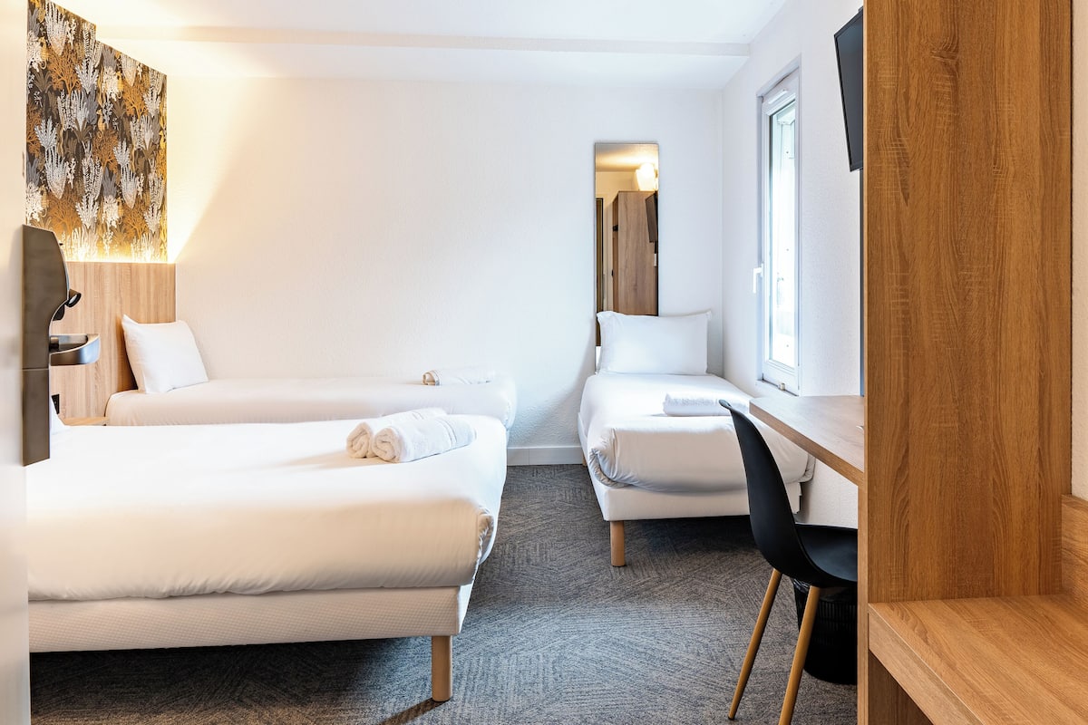 Una habitació d'hotel amb dos llits, una taula i una cadira.