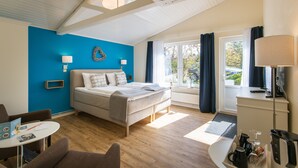 Habitación de hotel moderna con cama, escritorio, silla, mesa y ventana con cortinas.
