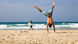 Escena de playa con una persona haciendo un pino.