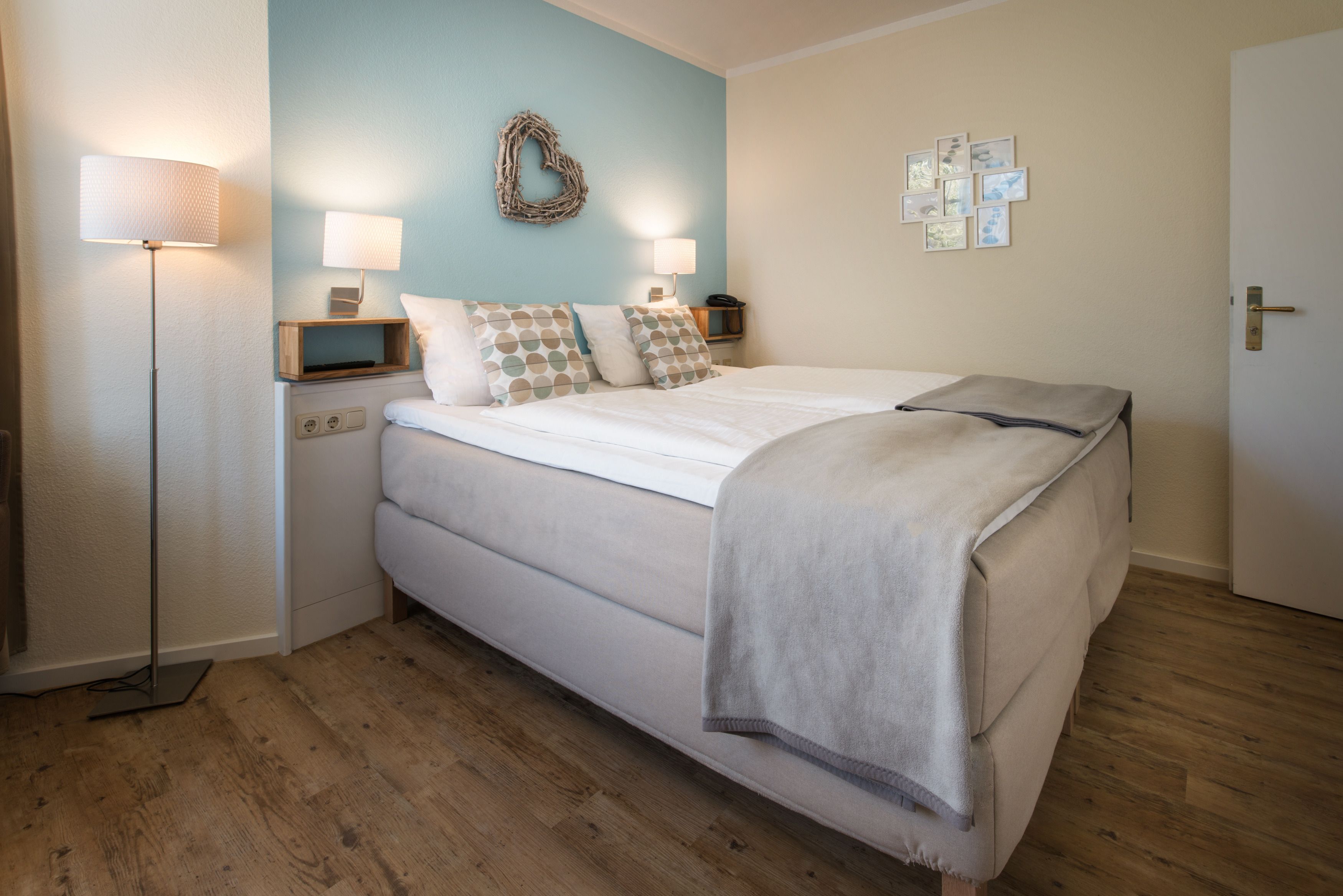 Une chambre à coucher avec un lit, des lampes de chevet, un décor mural en forme de cœur et une porte.