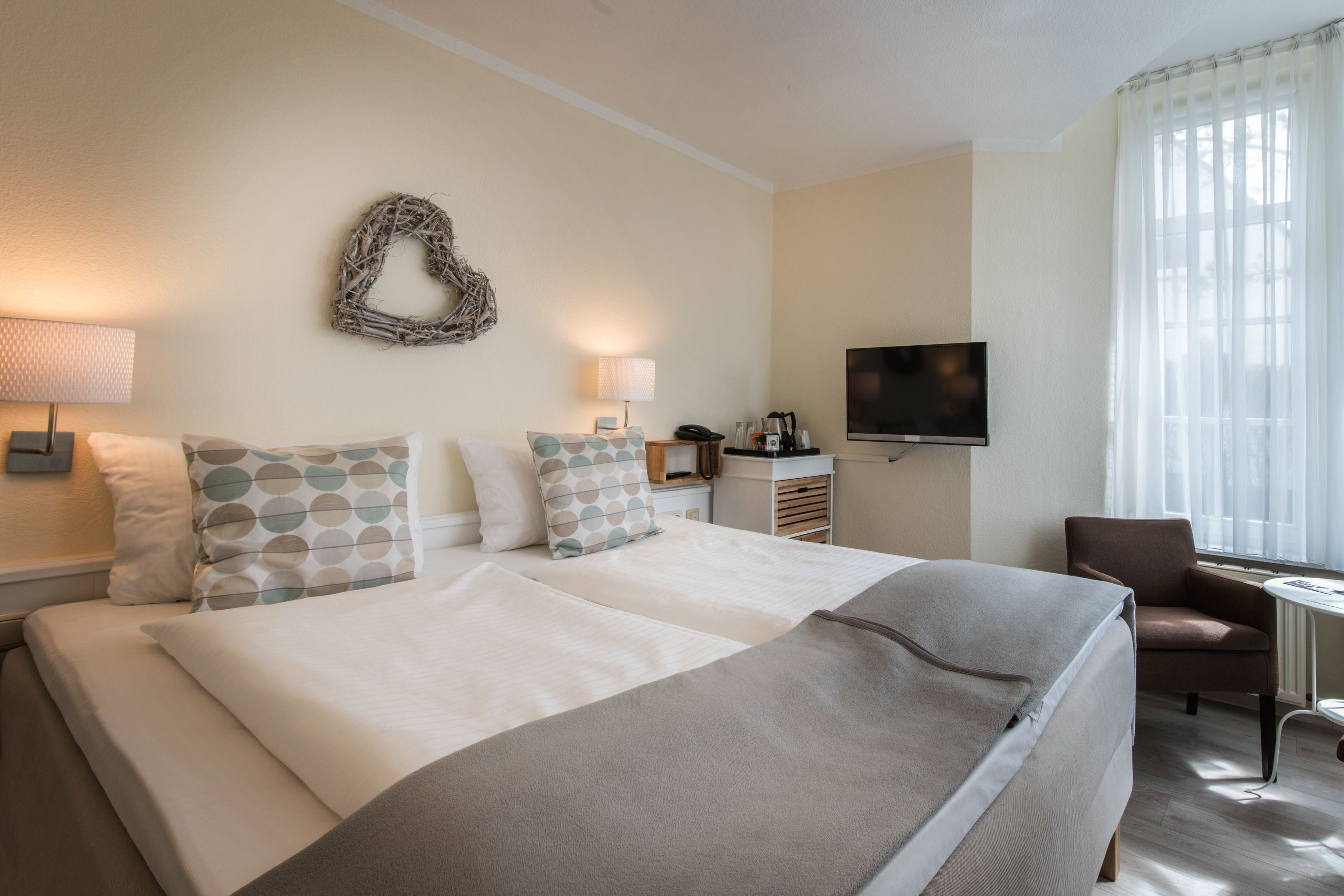 Camera d'albergo con un letto grande, due abat-jour, una TV a schermo piatto, un tavolino e una sedia.