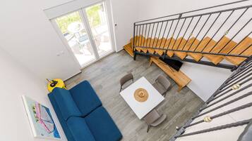 Una sala de estar moderna con un sofá azul, una mesa blanca y una escalera con peldaños de madera.