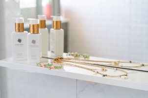 A display of skincare products and jewelry on a white marble counter.