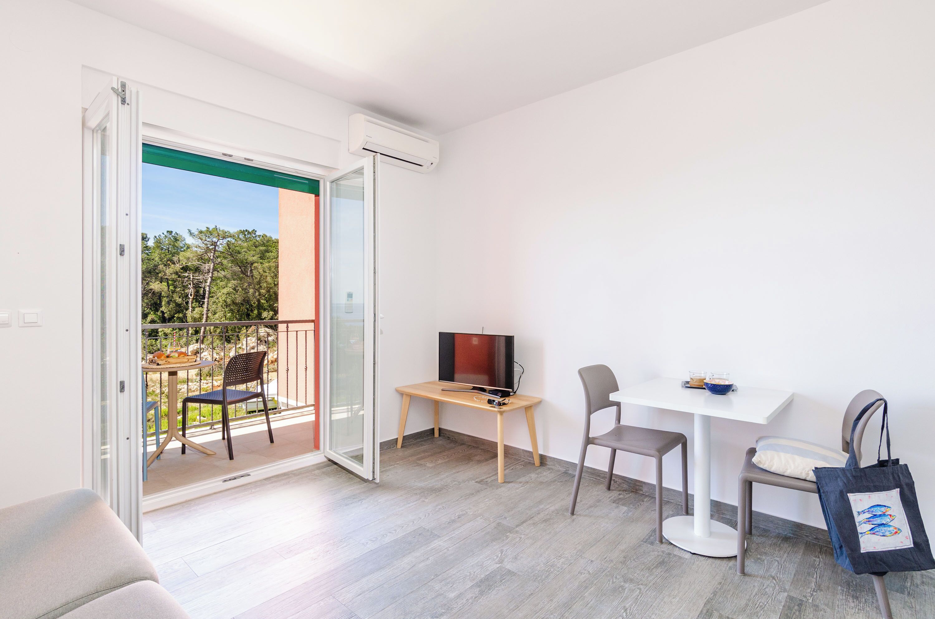 A balcony with a table, chairs, and a TV.