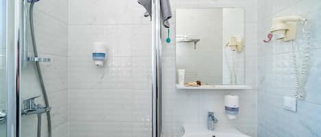 A modern bathroom with a glass-enclosed shower, a white sink, a mirror, and a telephone.