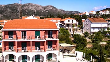 A hotel with a red-tiled roof, multiple balconies, and a pool area.