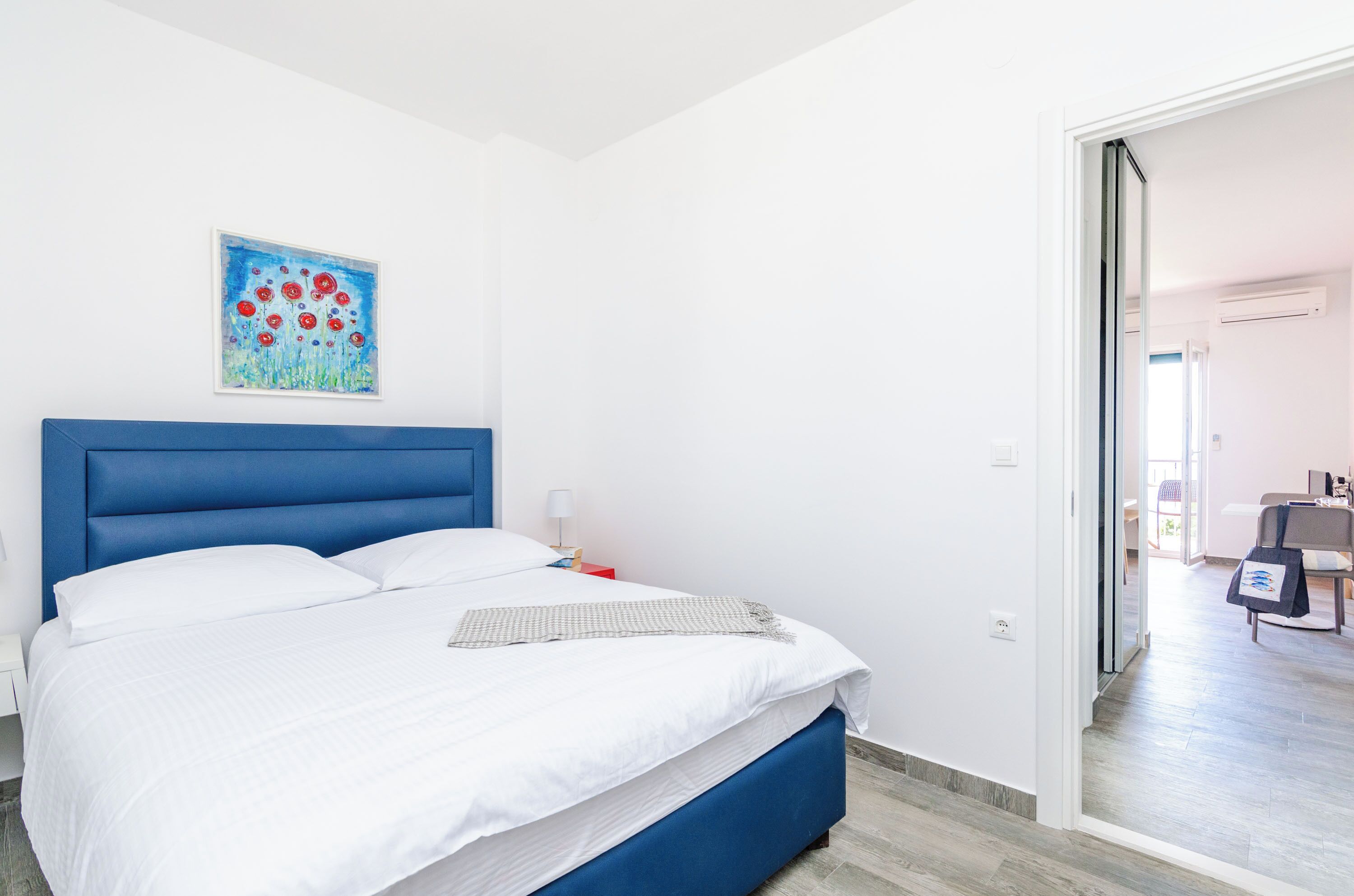 Una habitación de hotel moderna con una cama grande, un cabecero azul y un cuadro en la pared.