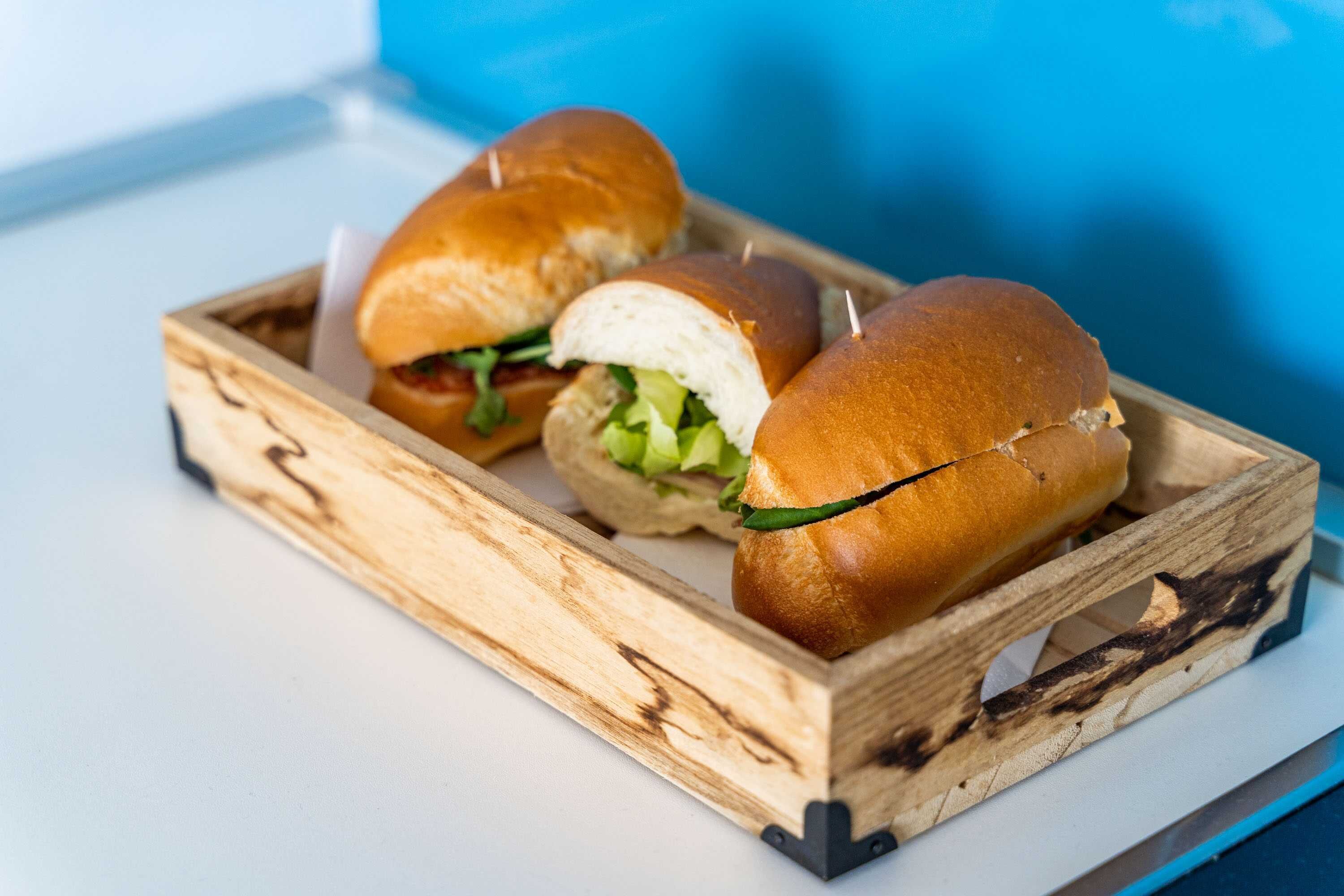 Drei Sandwiches in einer Holzkiste.