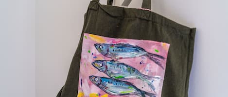 Una bolsa de tela con una pintura colorida de peces sobre un fondo rosa.