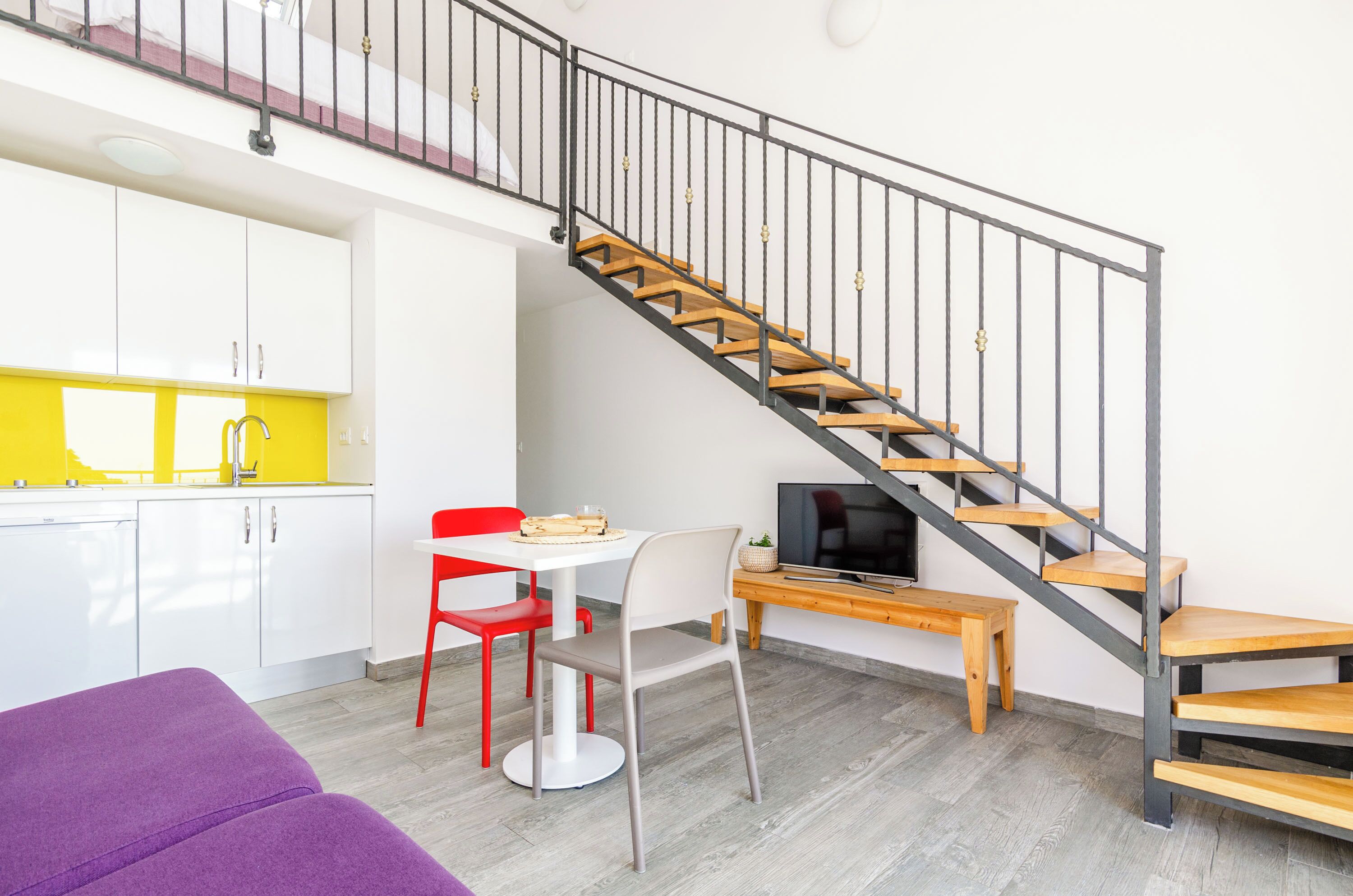 A modern apartment with a kitchen, dining area, and a staircase.