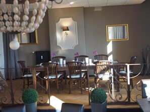 A dining area with a long table, multiple chairs, and decorative elements like a chandelier and potted plants. - Hotel Sehnder Hof (Sehnde)