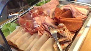 Ein Buffet mit verschiedenen Fleischsorten, darunter Scheibenkäse, Prosciutto und ein Braten.