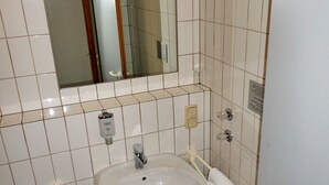 Ein Badezimmer mit weißem Waschbecken, Spiegel und Fliesenwänden.