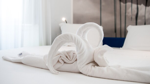 Un lit bien fait, avec des serviettes blanches disposées en forme de cœur.