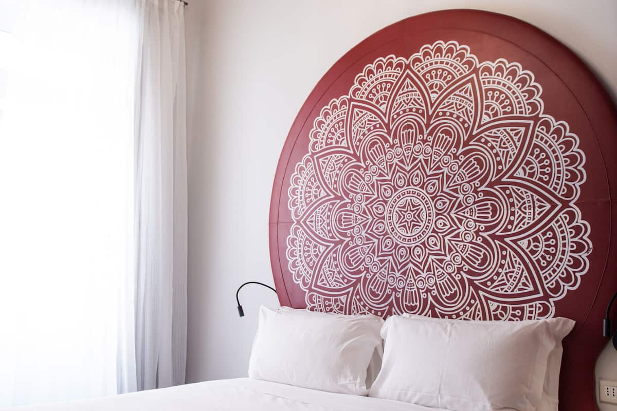 Ein Schlafzimmer mit einem großen Bett, einem verzierten Kopfteil und einer Chandelüster.
