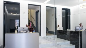 Un espace d’accueil moderne avec un escalier en marbre, un comptoir d’accueil et un escalier menant à l’étage supérieur.