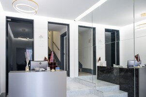 Ein moderner Empfangsbereich mit einer Marmortreppe, einem Empfangstresen und einer Treppe zu einer oberen Etage.