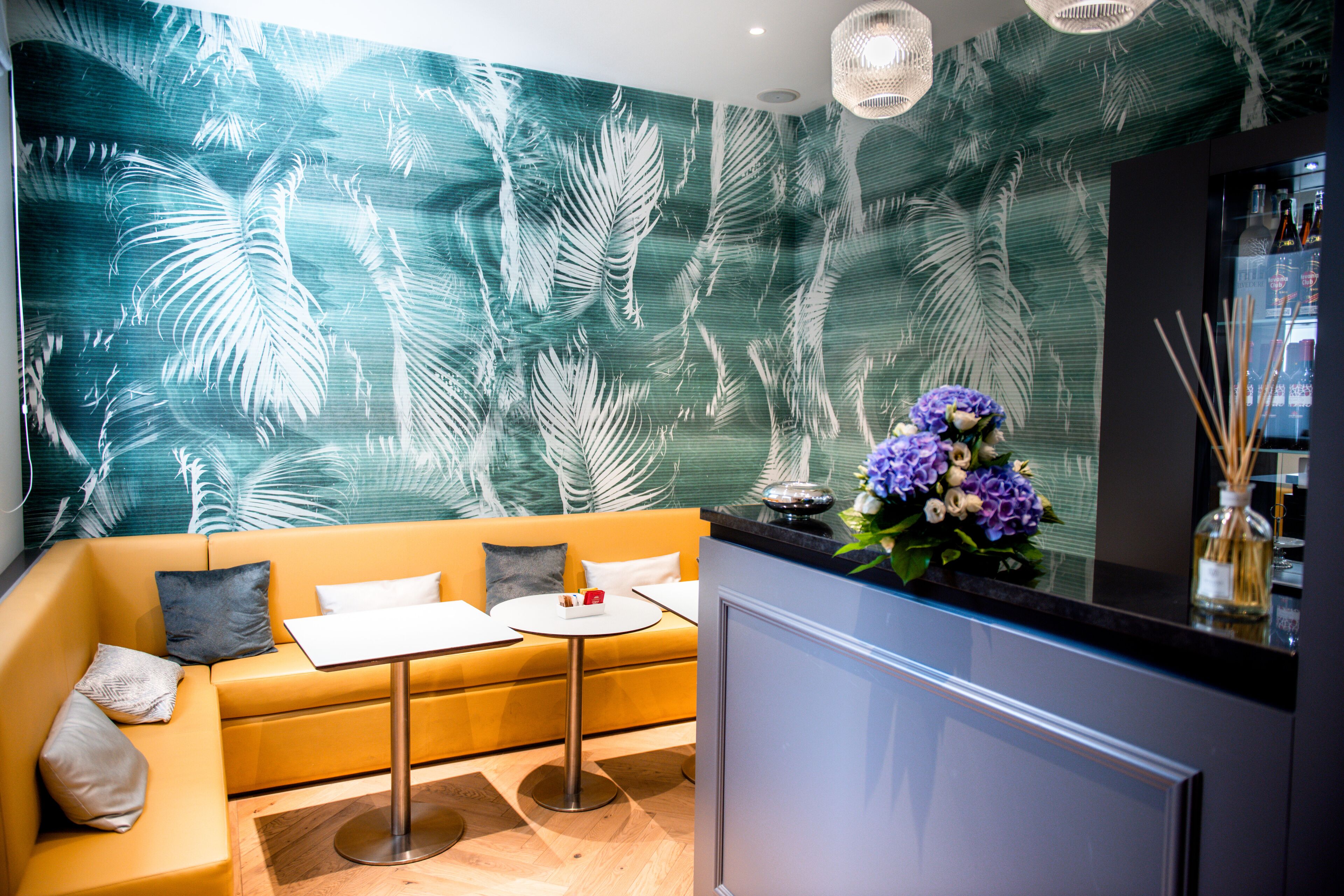 A modern interior with a sofa, a small round table, and a decorative wall with a leaf pattern.