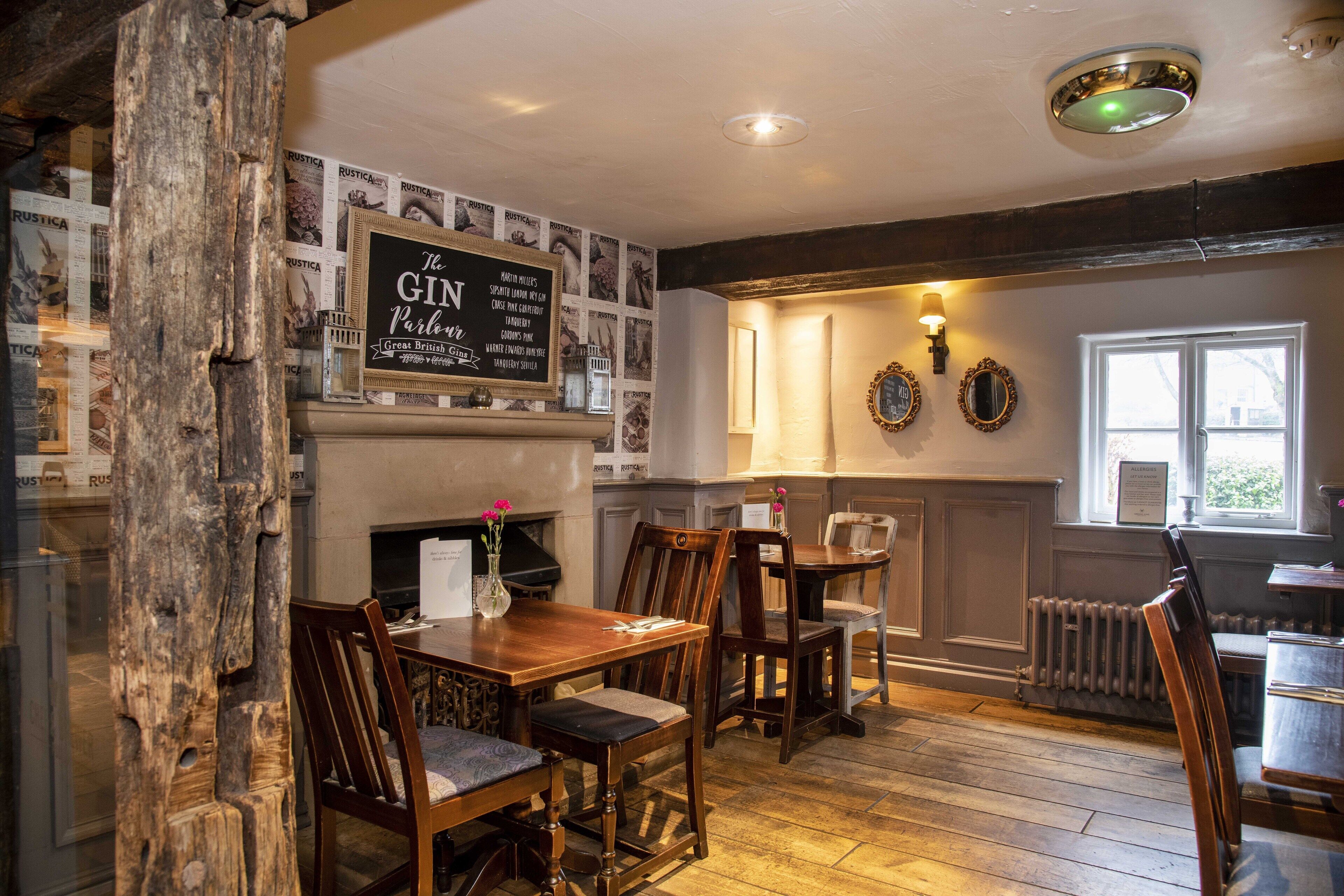 A traditional pub interior with wooden furniture, a blackboard menu, and a fireplace.