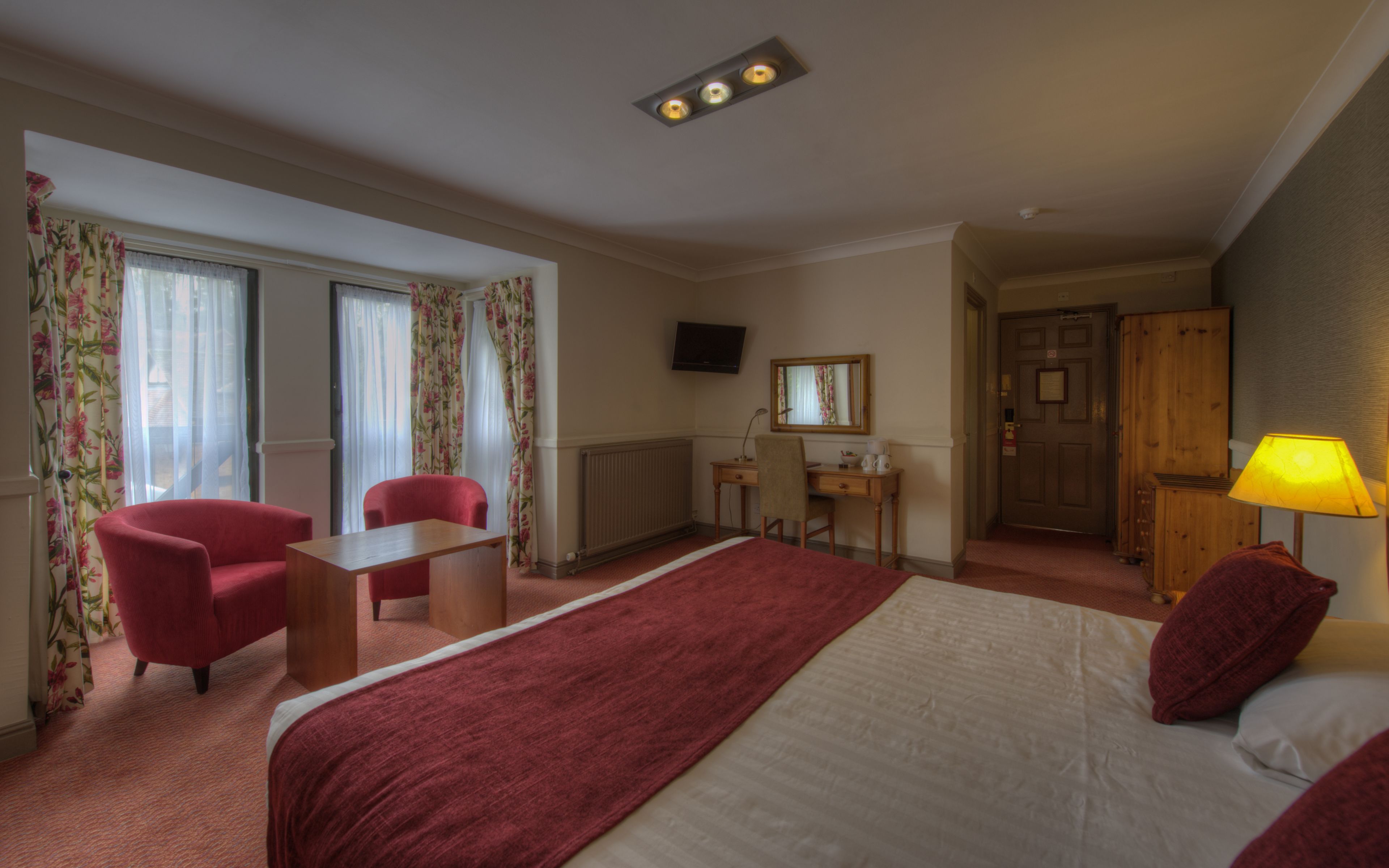 A hotel room with a bed, a desk, a chair, a television, and a wardrobe.