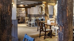 A rustic interior with exposed wooden beams, a dining area with tables and chairs, and a large mirror on the wall. - The Old Mill by Chef and Brewer Collection (Coventry)