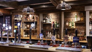 A bar area with multiple beer taps, shelves with various liquor bottles, and a wooden interior. - The Old Mill by Chef and Brewer Collection (Coventry)