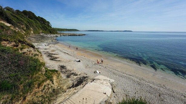 A coastal beach with clear water, rocky shore, and greenery. - Hotel Meudon (Falmouth)