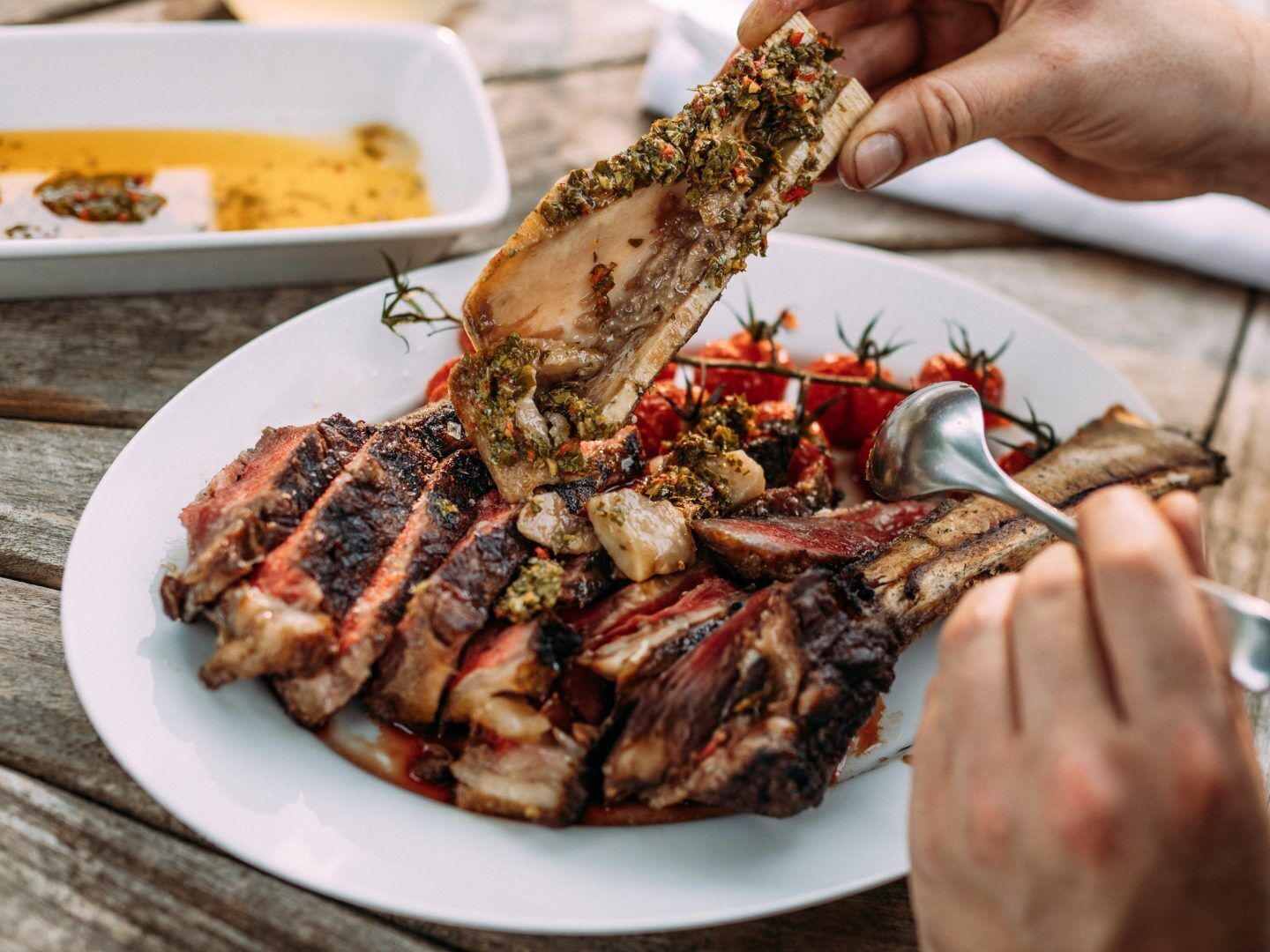 A plate of grilled meat with a herb crust, served on a wooden table.