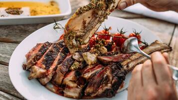 A plate of grilled meat with a herb crust, served on a wooden table.