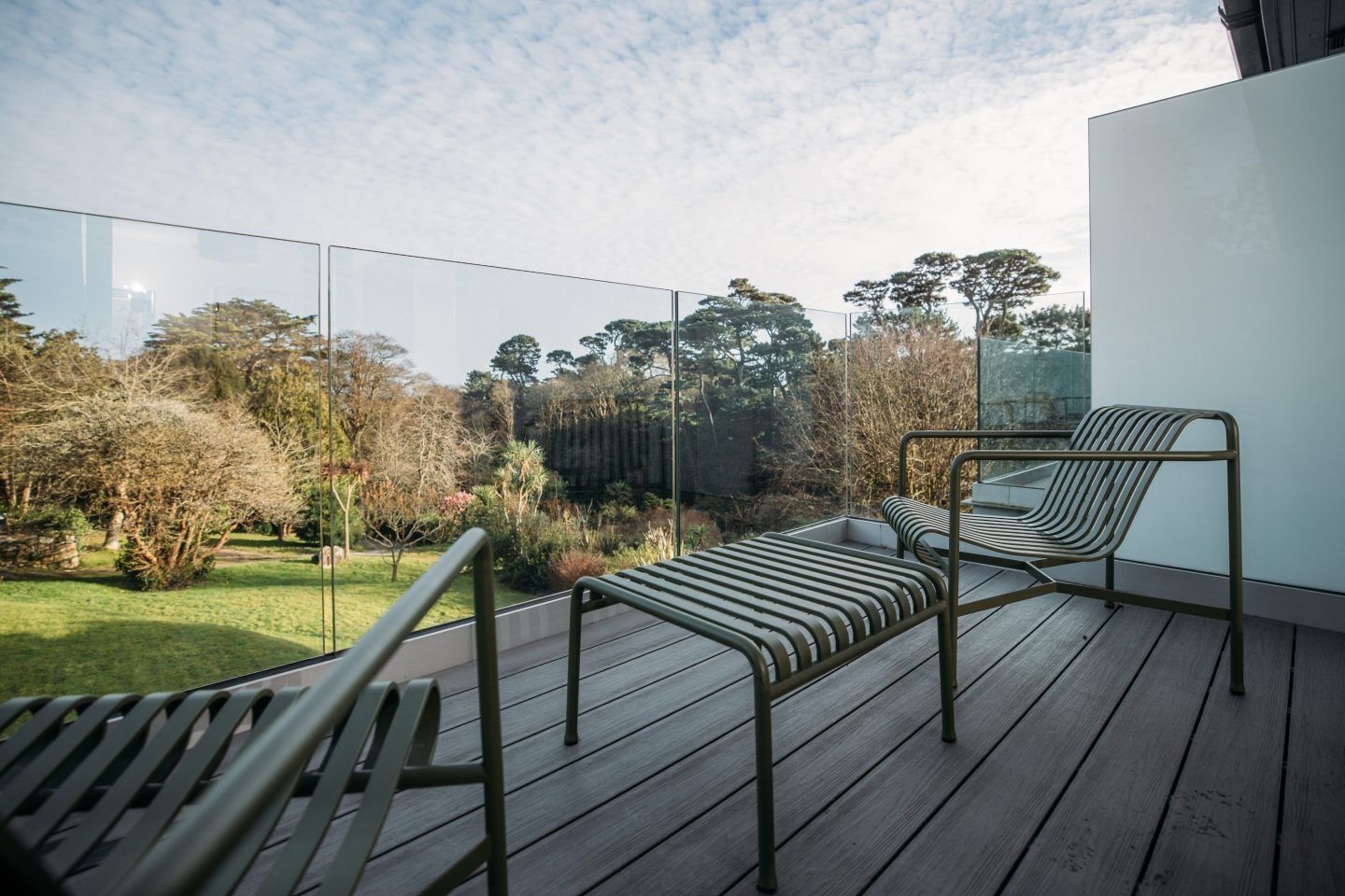 Un balcon avec deux chaises à armature métallique et une terrasse en bois.