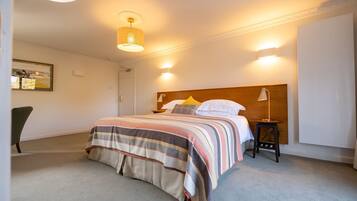 Een netjes ingerichte slaapkamer met een bed, nachtkastje, lamp en een stoel.