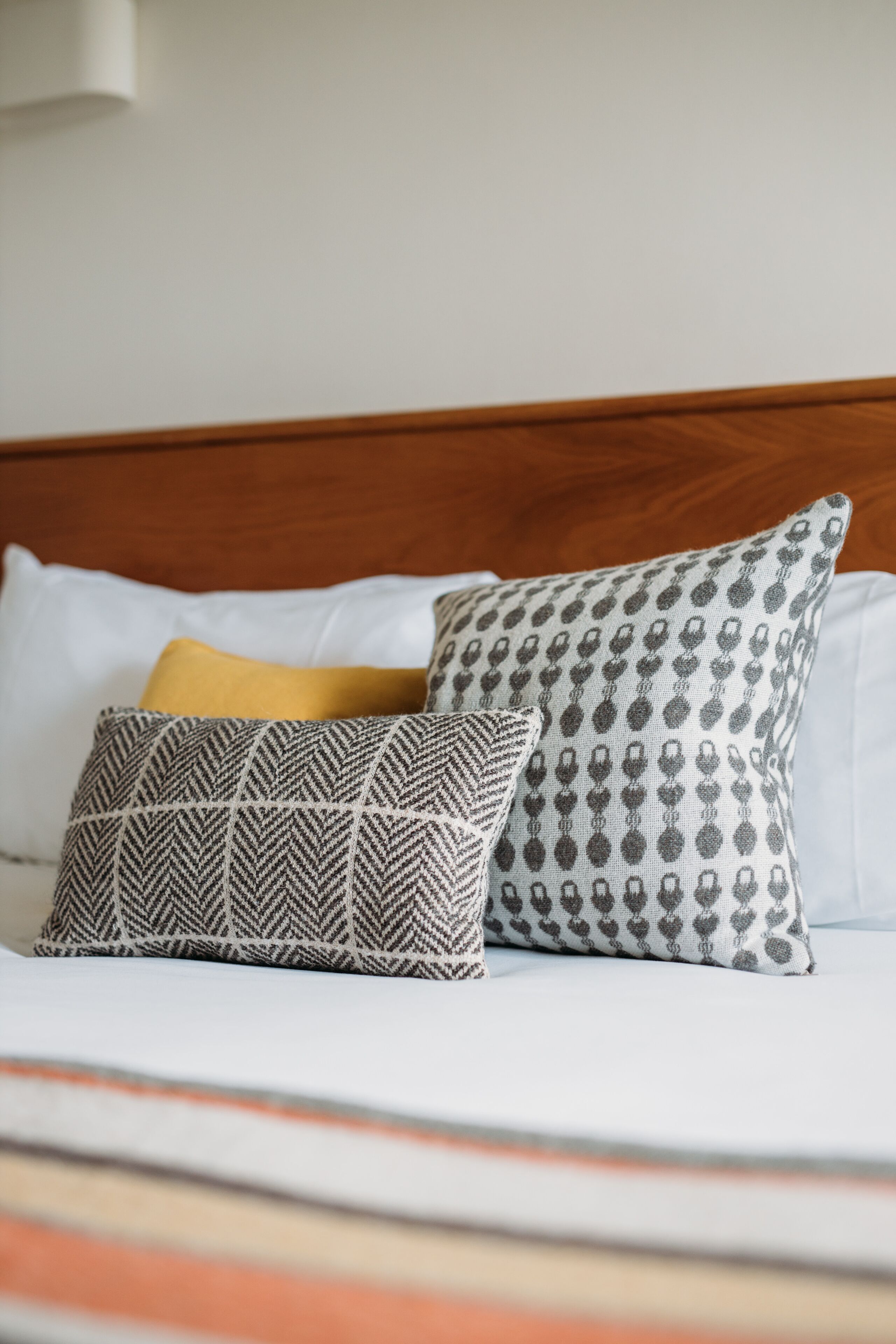 A bed with a wooden headboard, two patterned pillows, and a striped blanket.