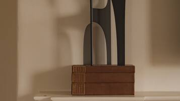 A fireplace mantel with a modern sculpture and three books.