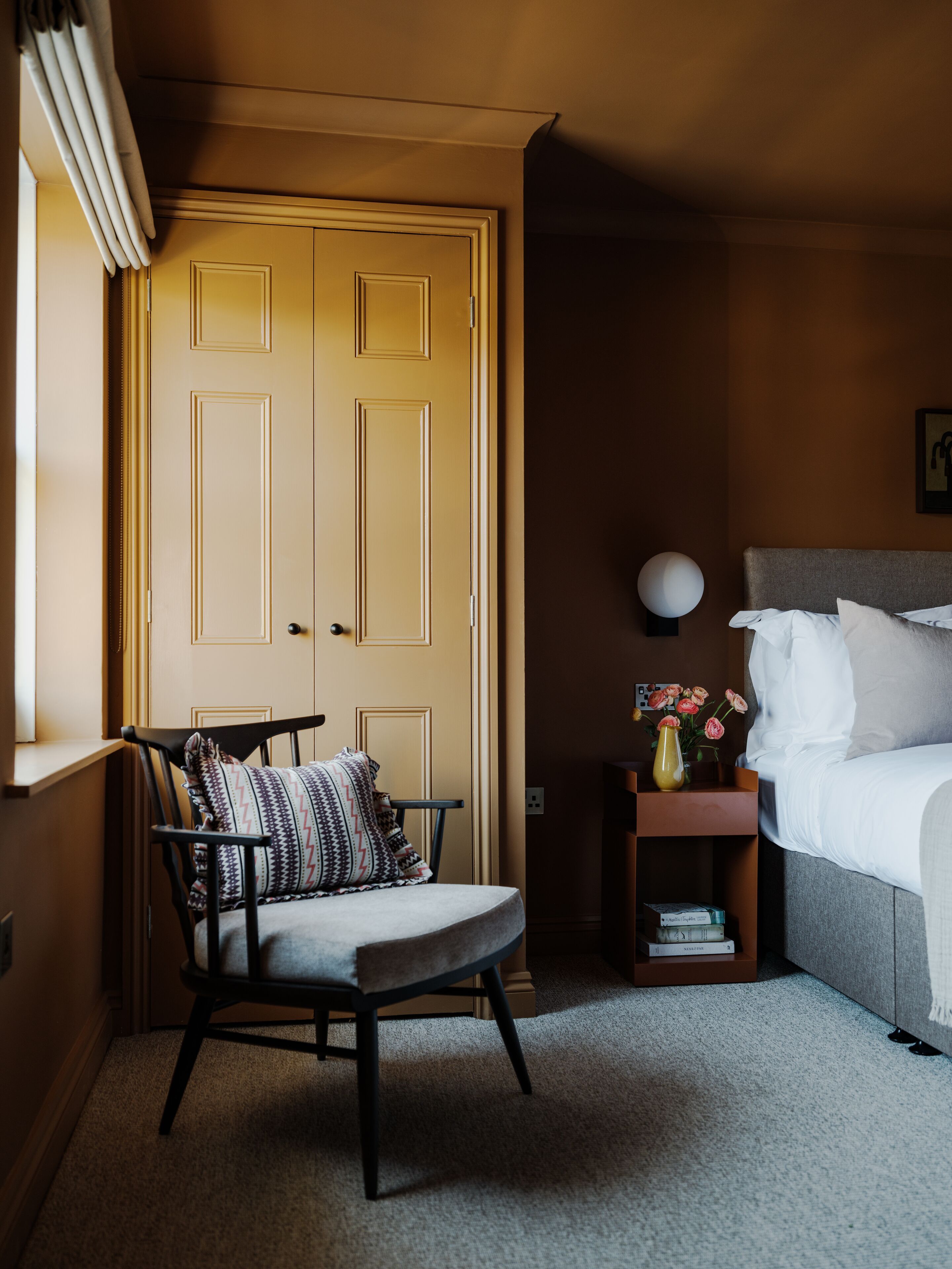 A bedroom with a bed, a chair, a nightstand, and a door.